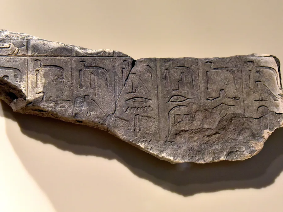 Painted limestone relief fragment with Egyptian Pyramid Texts hieroglyphs from Saqqara.